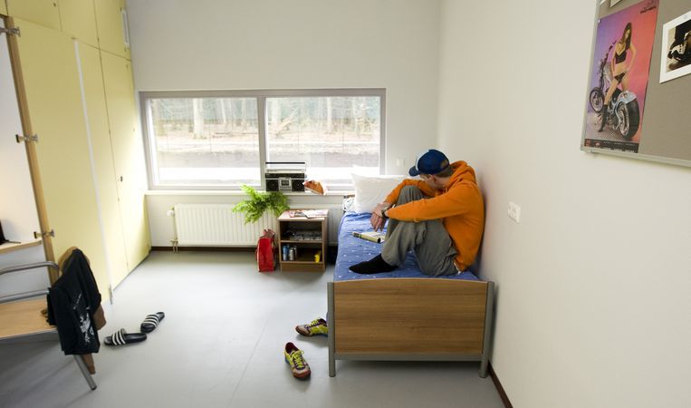 Jongere met verstandelijke beperking zittend op bed in zijn kamer