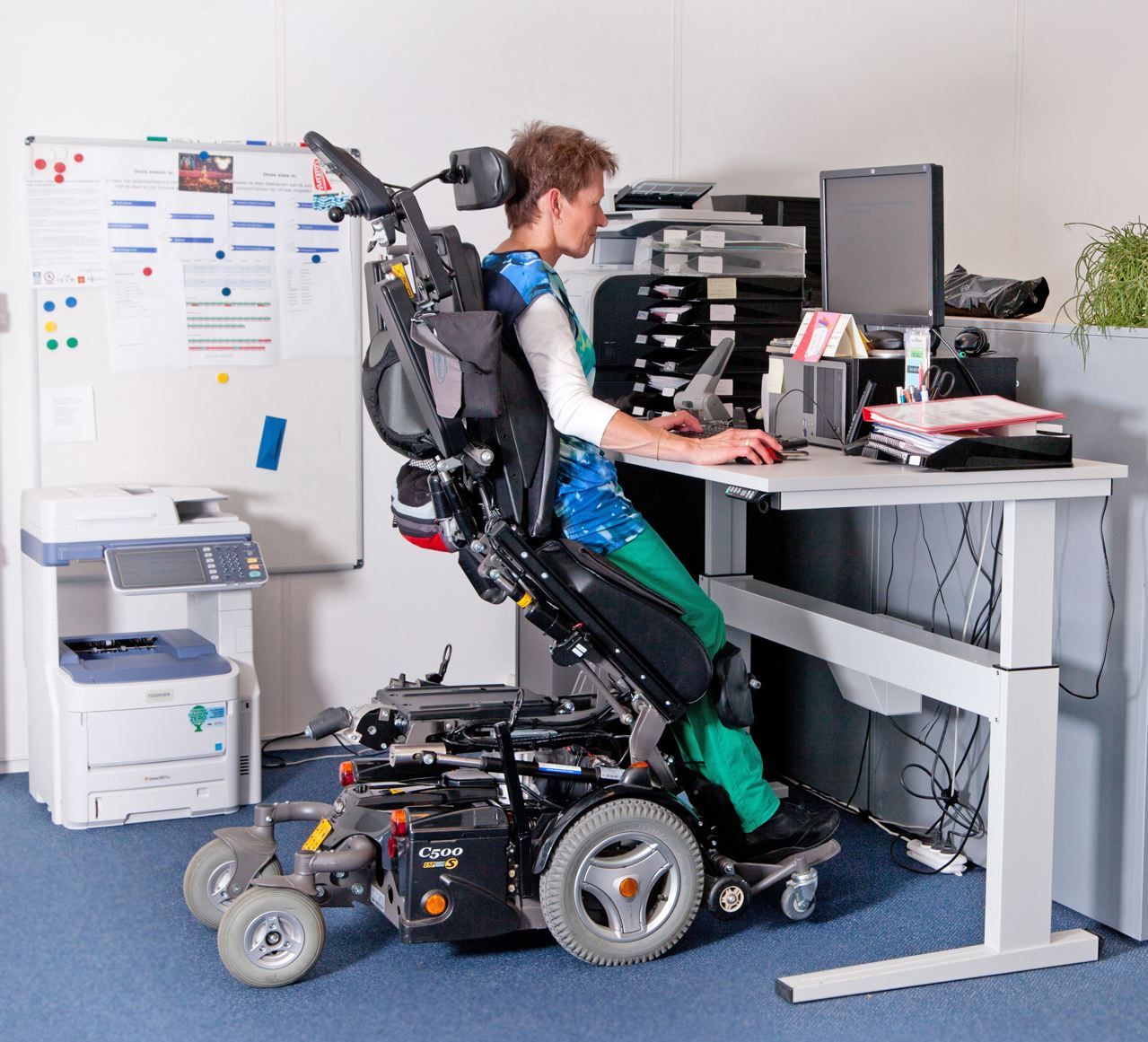 Mevrouw met een beperking aan het werk met speciaal aangepast bureau