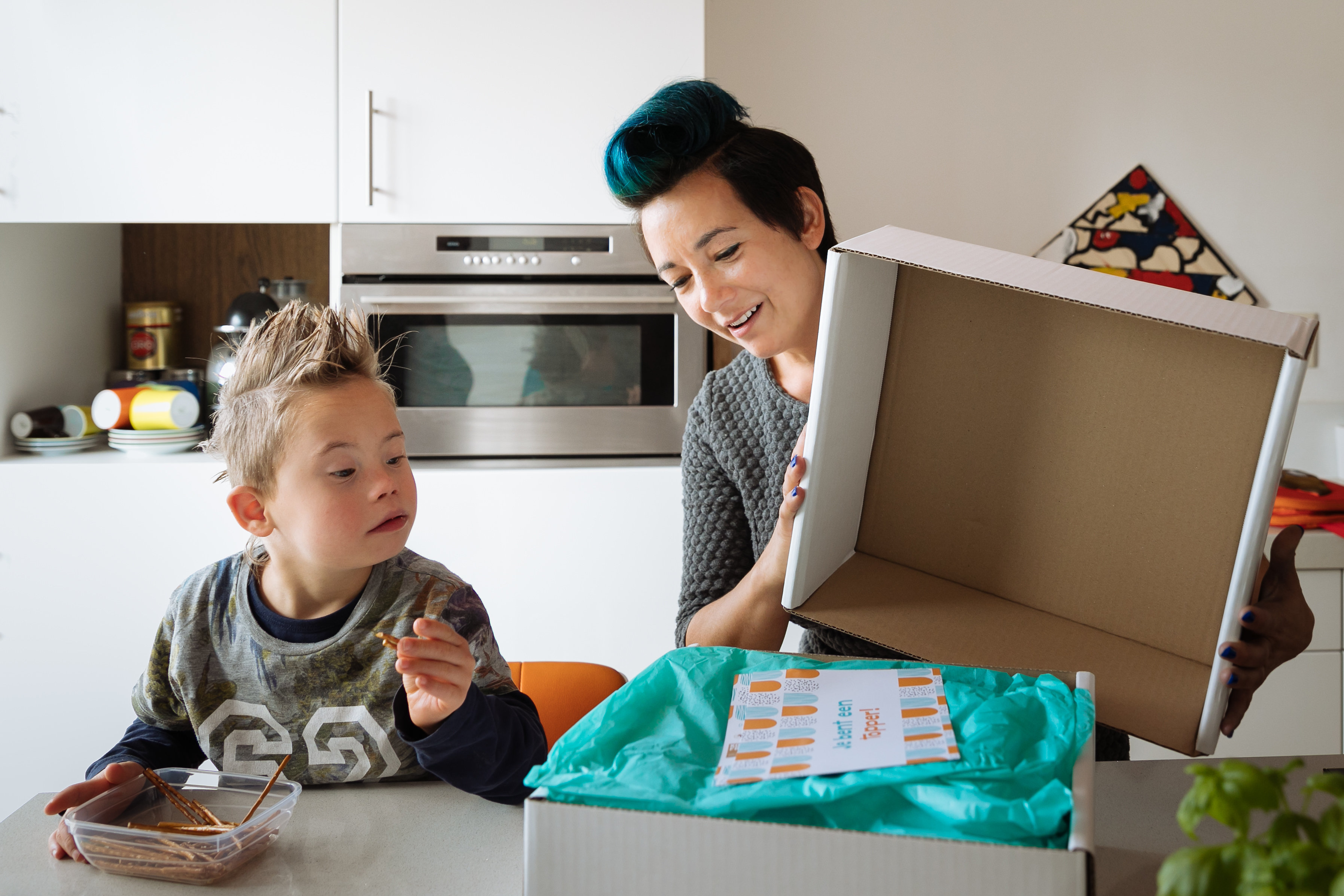 Mevrouw maakt samen met zoon doos Gebaar van Waardering open.