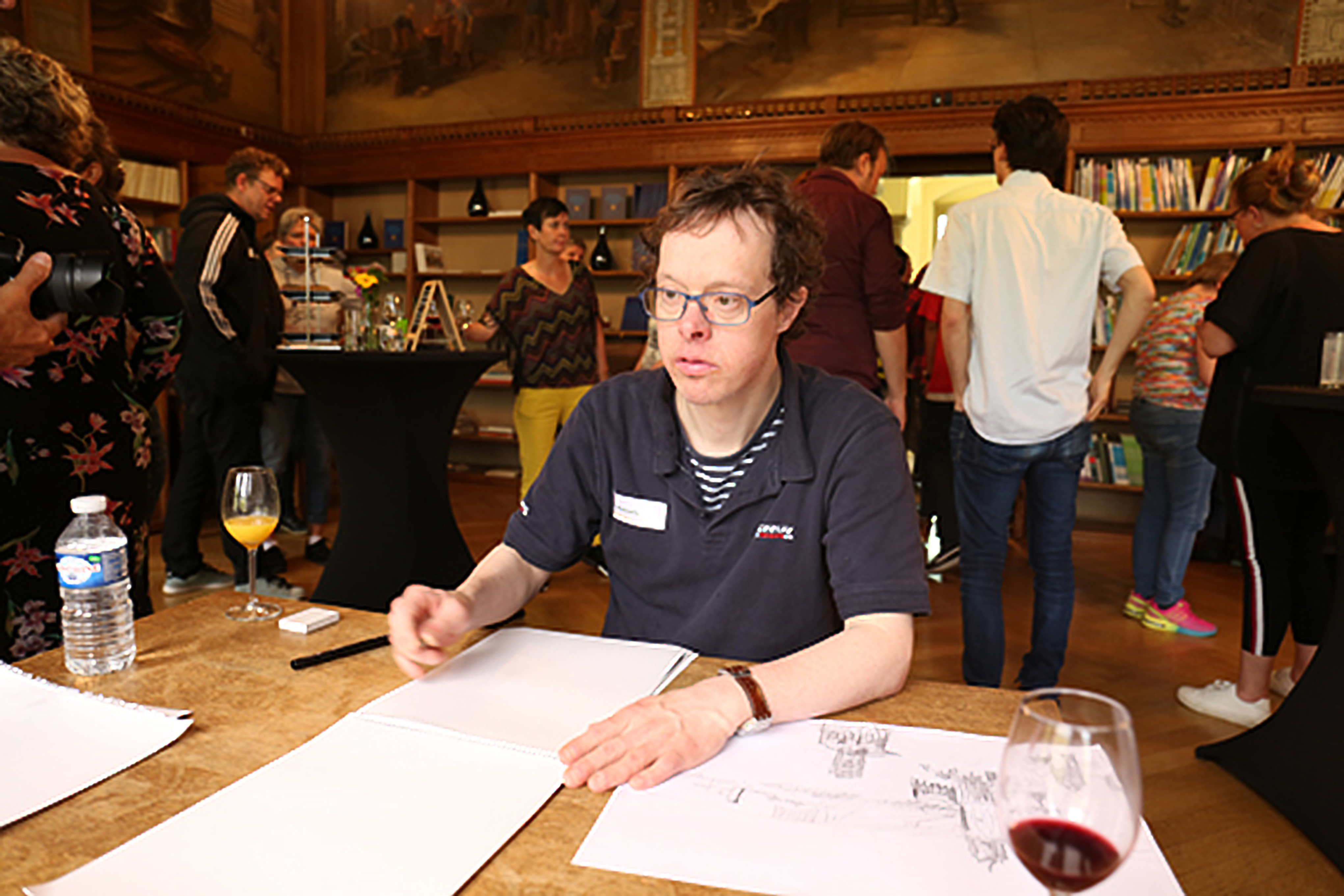 Kunstenaar Derk Wessels tekent aan tafel.