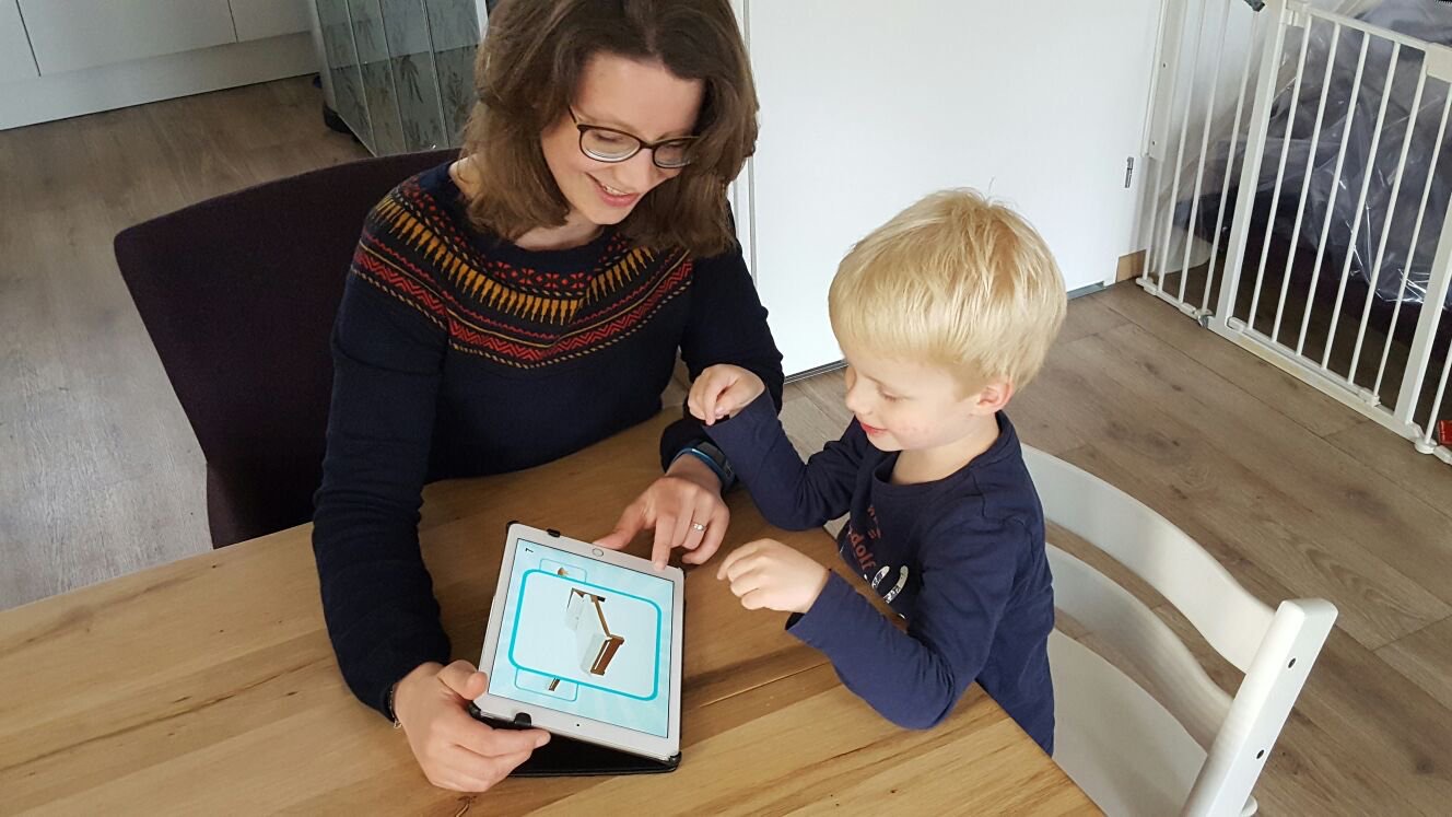 Moeder en Zoon gebruiken Speakaboo op de iPad aan tafel.