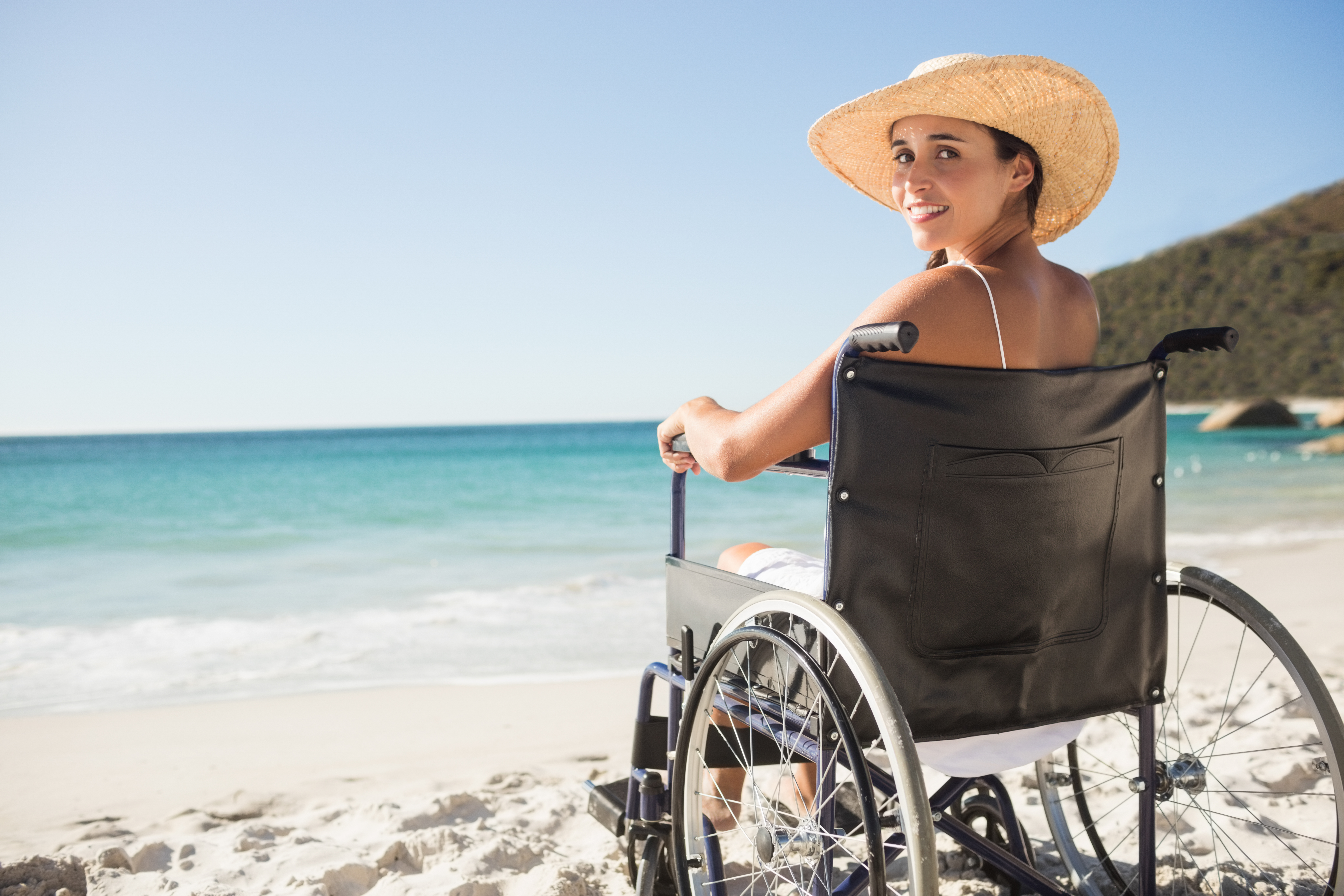 Jonge vrouw in een rolstoel op het strand.