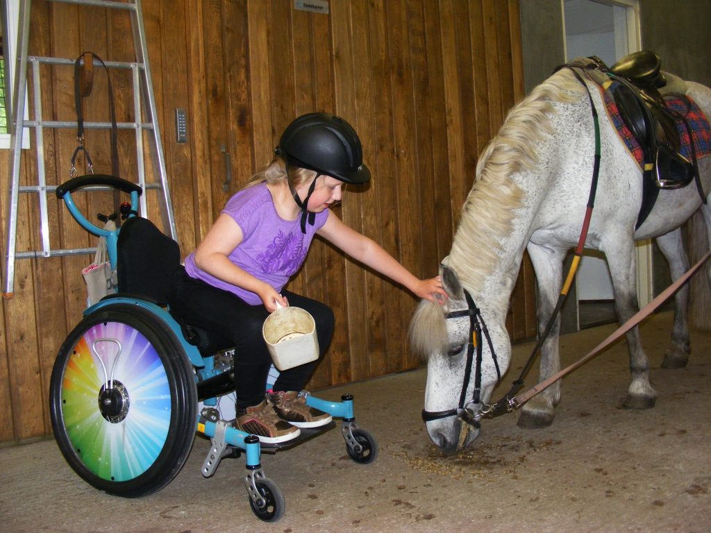 Meisje in een rolstoel bij een paard van Manege Onder de Linde