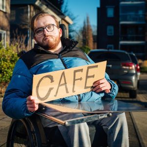 Man in rolstoel wil liften met het bordje café