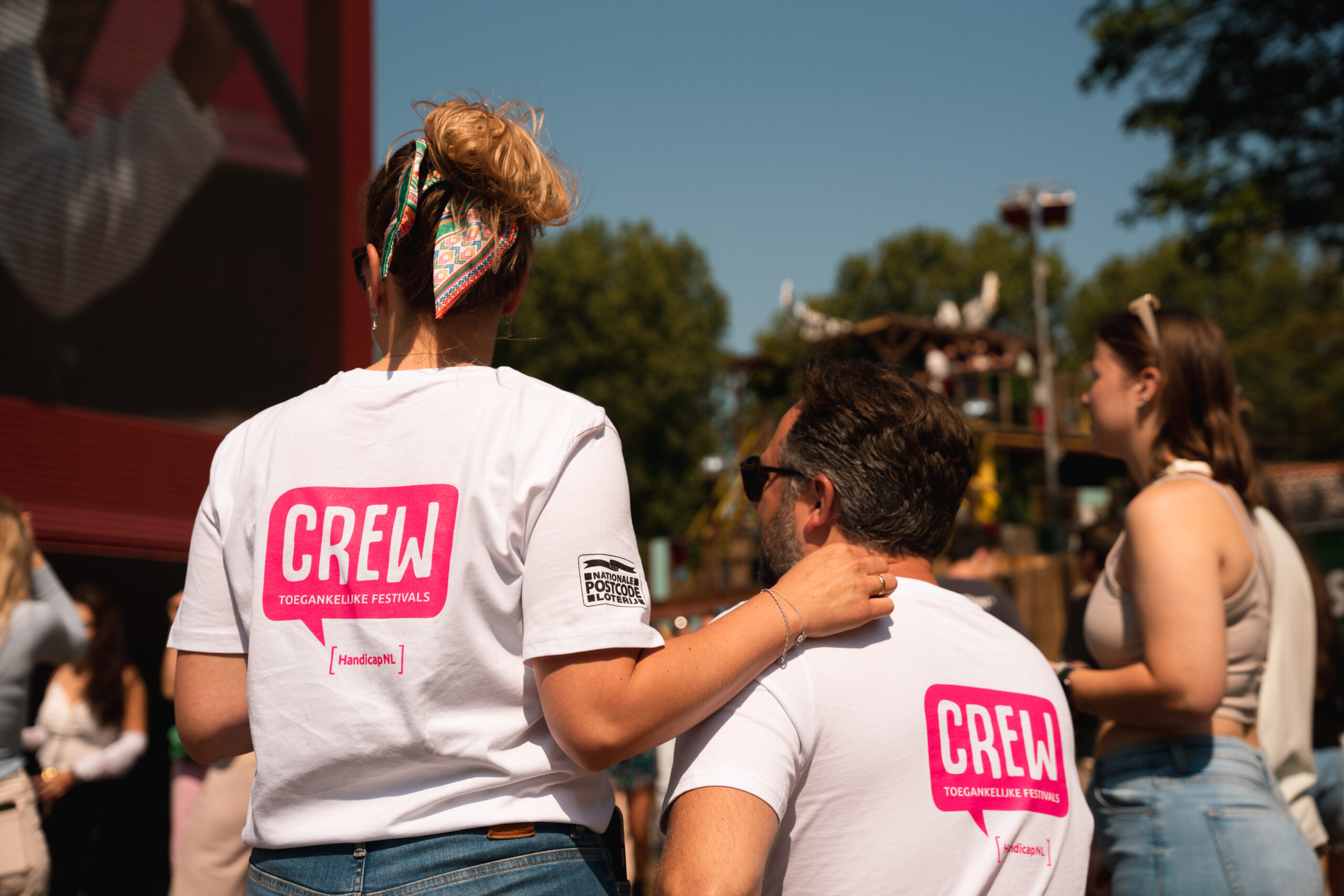 Twee crewleden van HandicapNL staan naar het optreden te kijken