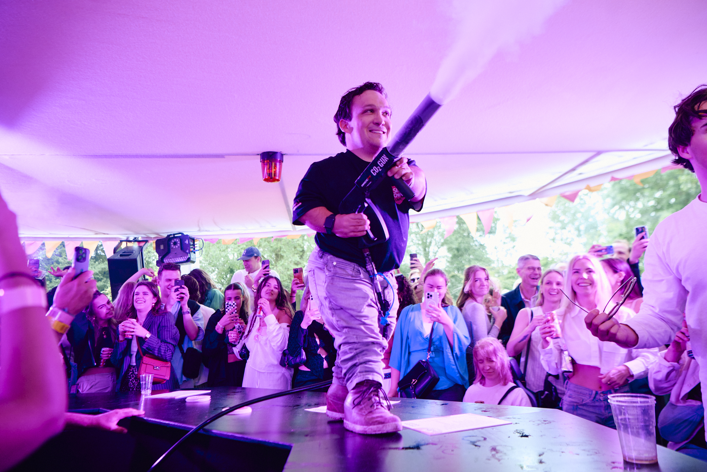 Een man met een fysieke beperking staat op de bar en heeft een rookmachine in zijn handen