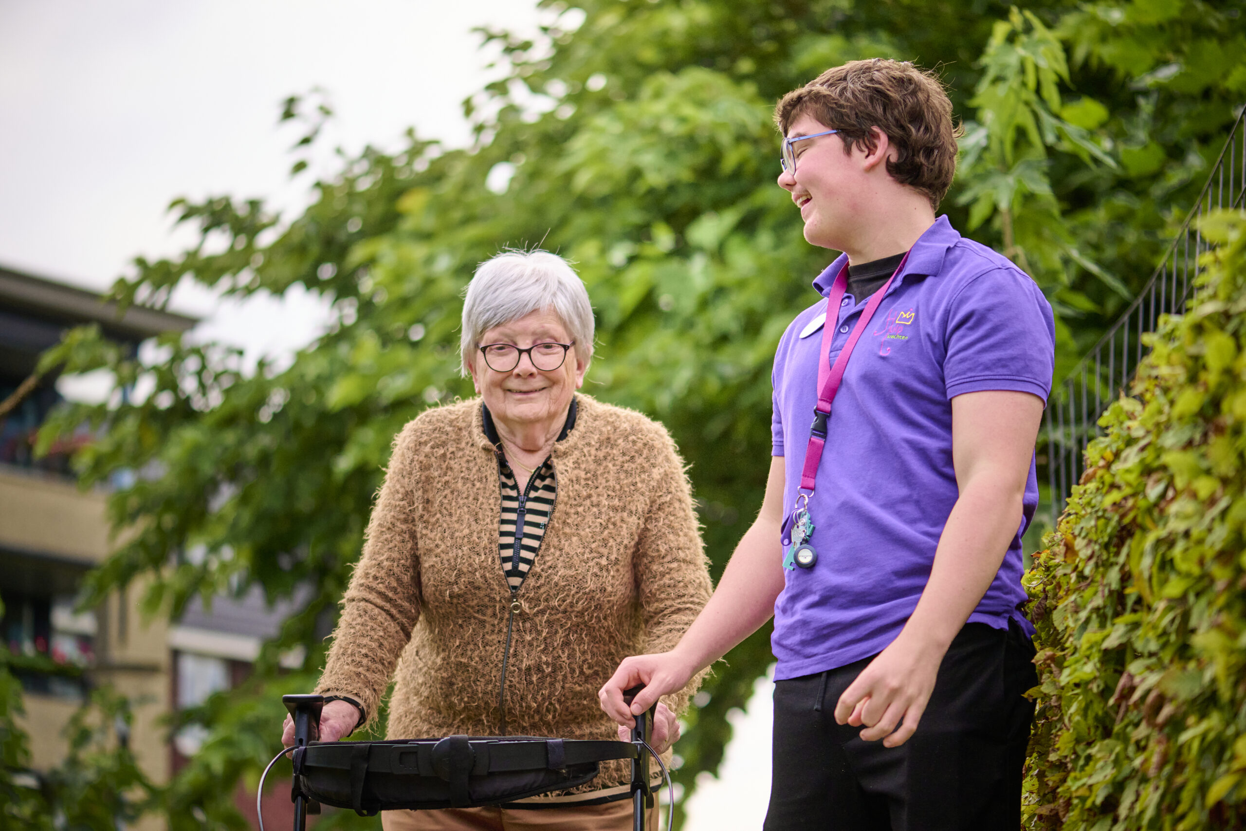 Een jongen met een verstandelijke beperking die werkzaam is bij Park Zuiderhout loopt samen met een oudere dame, ze lachen