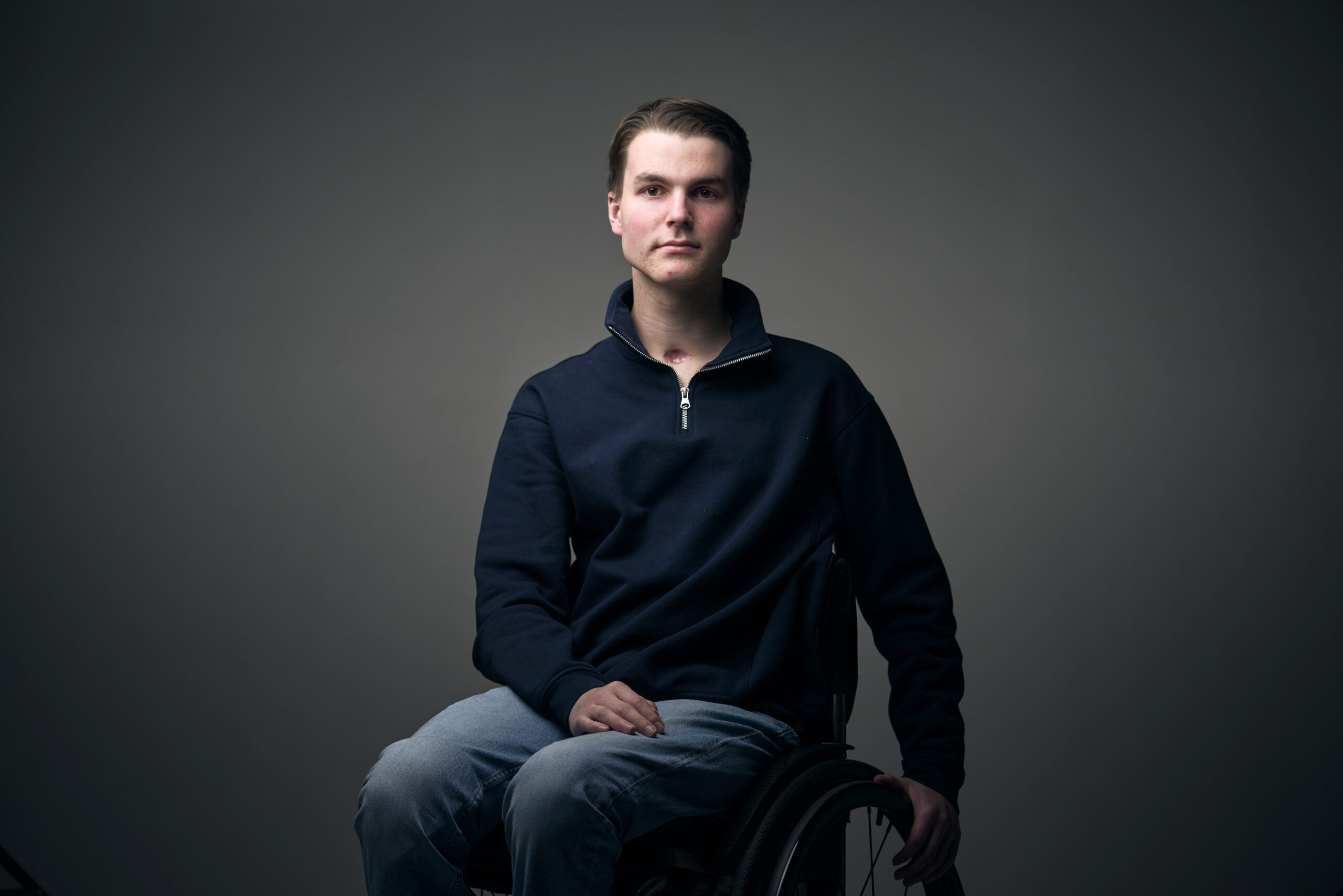Cees, een jongen met een fysieke beperking, die in een rolstoel zit en je recht aankijkt