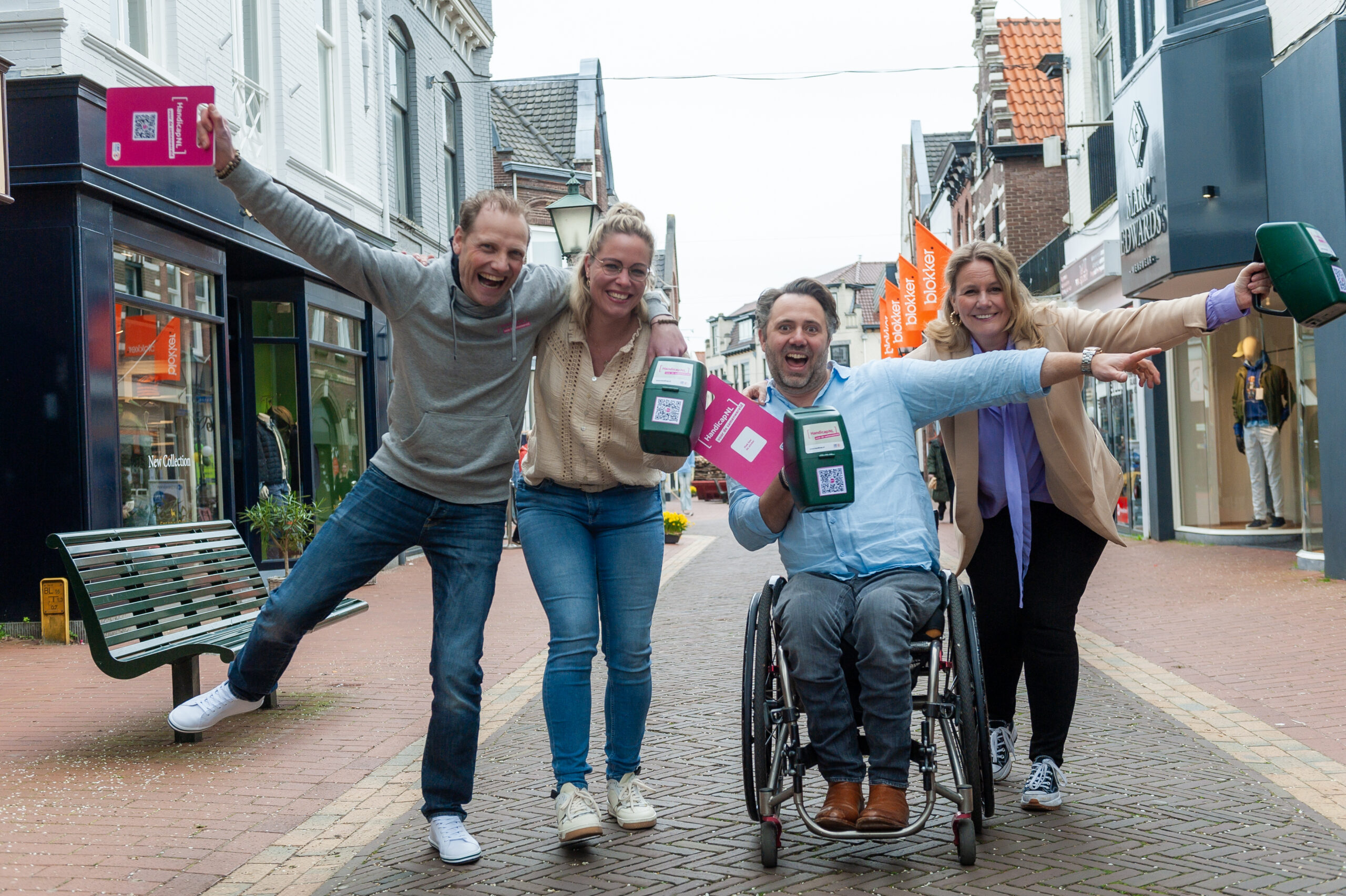 Het team van HandicapNL staat met collectebussen in een stad, ze omhelzen elkaar en zijn blij