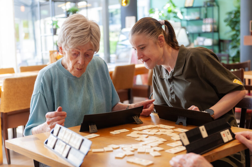 Een meisje met een verstandelijke beperking, die werkzaam is bij Prins Heerlijk speelt spelletjes met ouderen