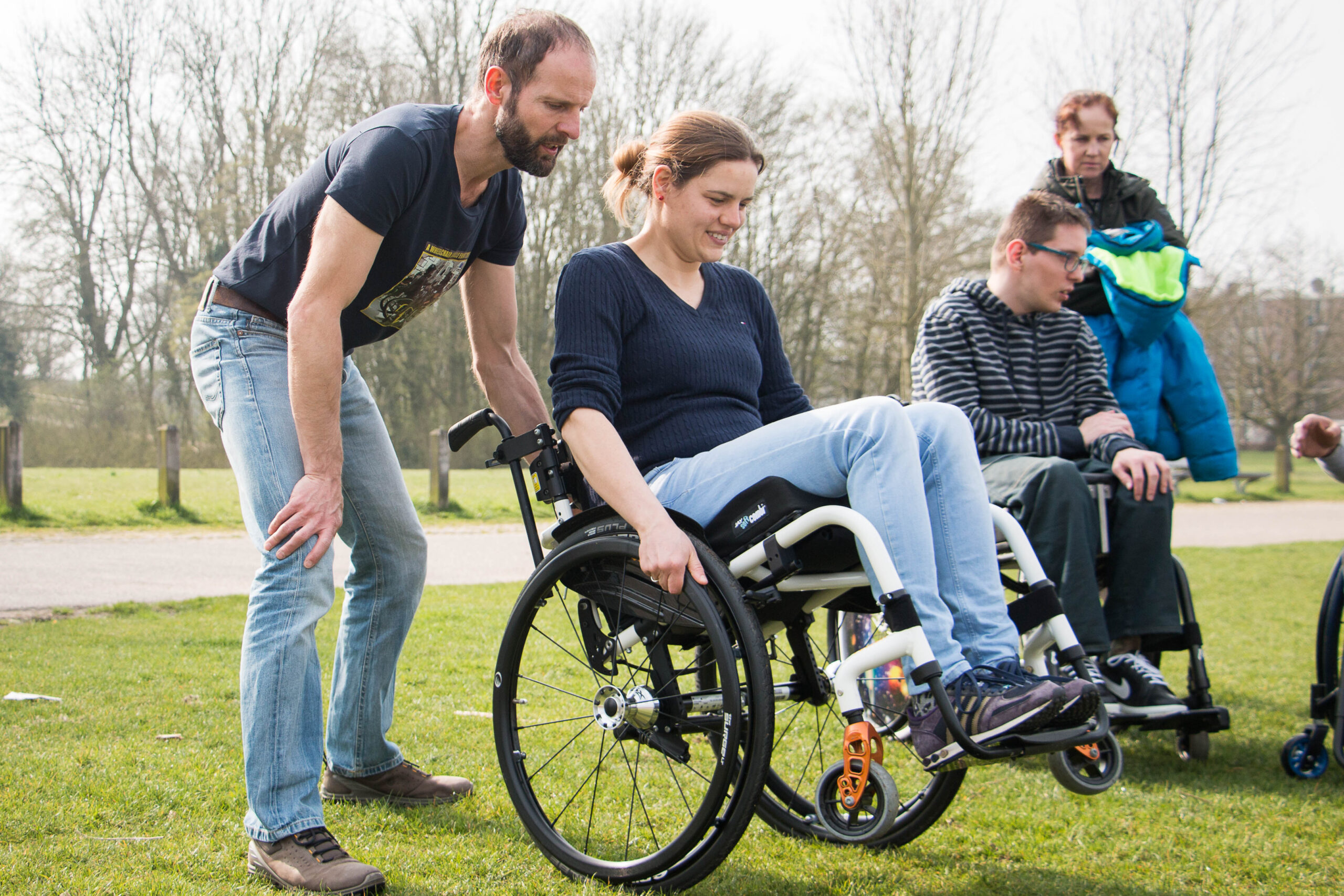 Een man begeleid een vrouw in een rolstoel