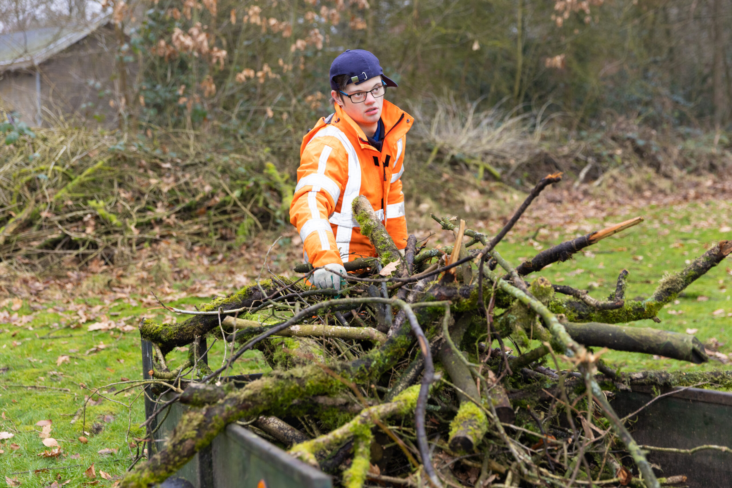 Een jongen met een verstandelijke beperking die werkzaam is bij Parc Spelderholt verzamelt takken