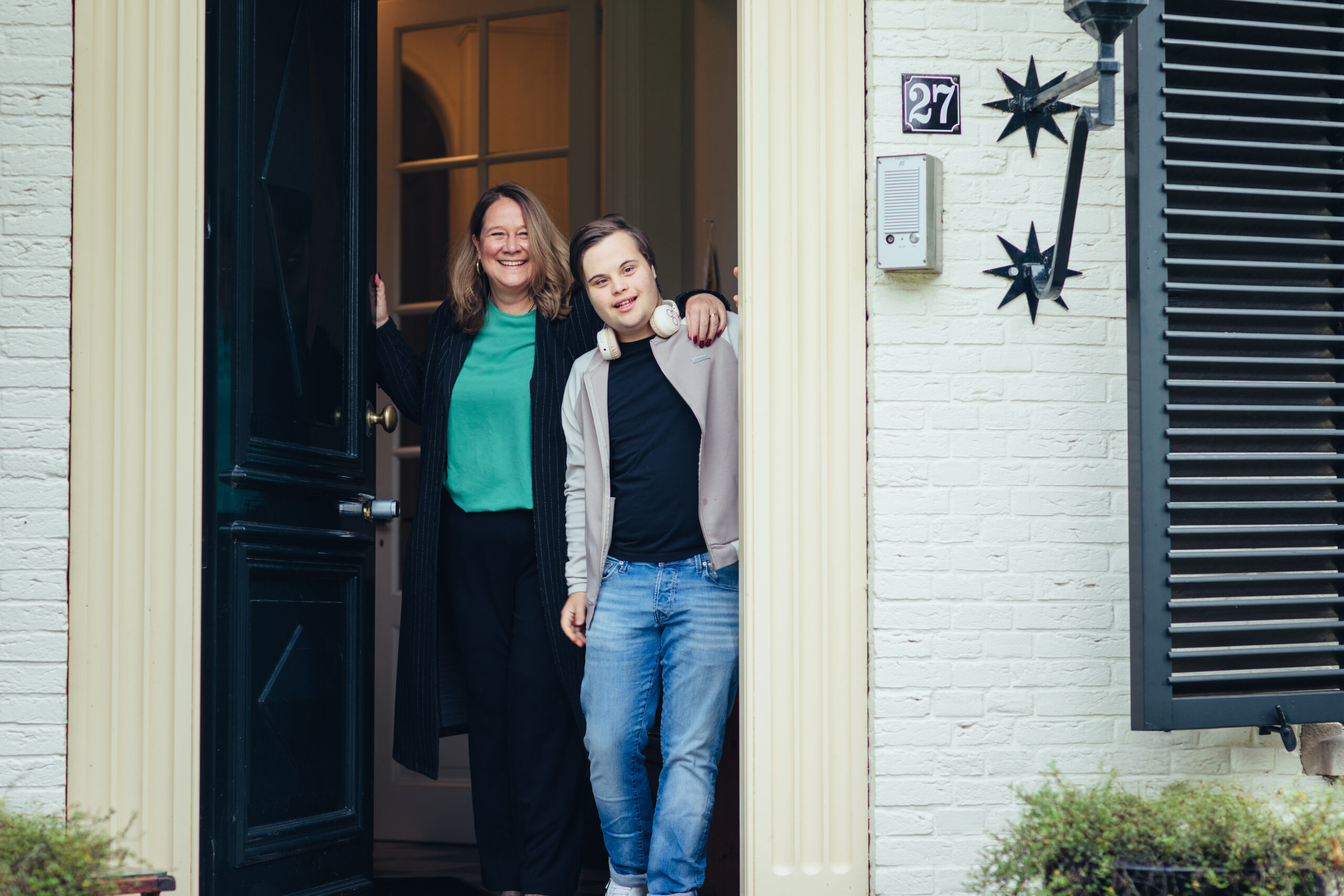 Linda Germs staat in de deuropening van een huis samen met haar zoon Lukas, een jongen met het syndroom van Down