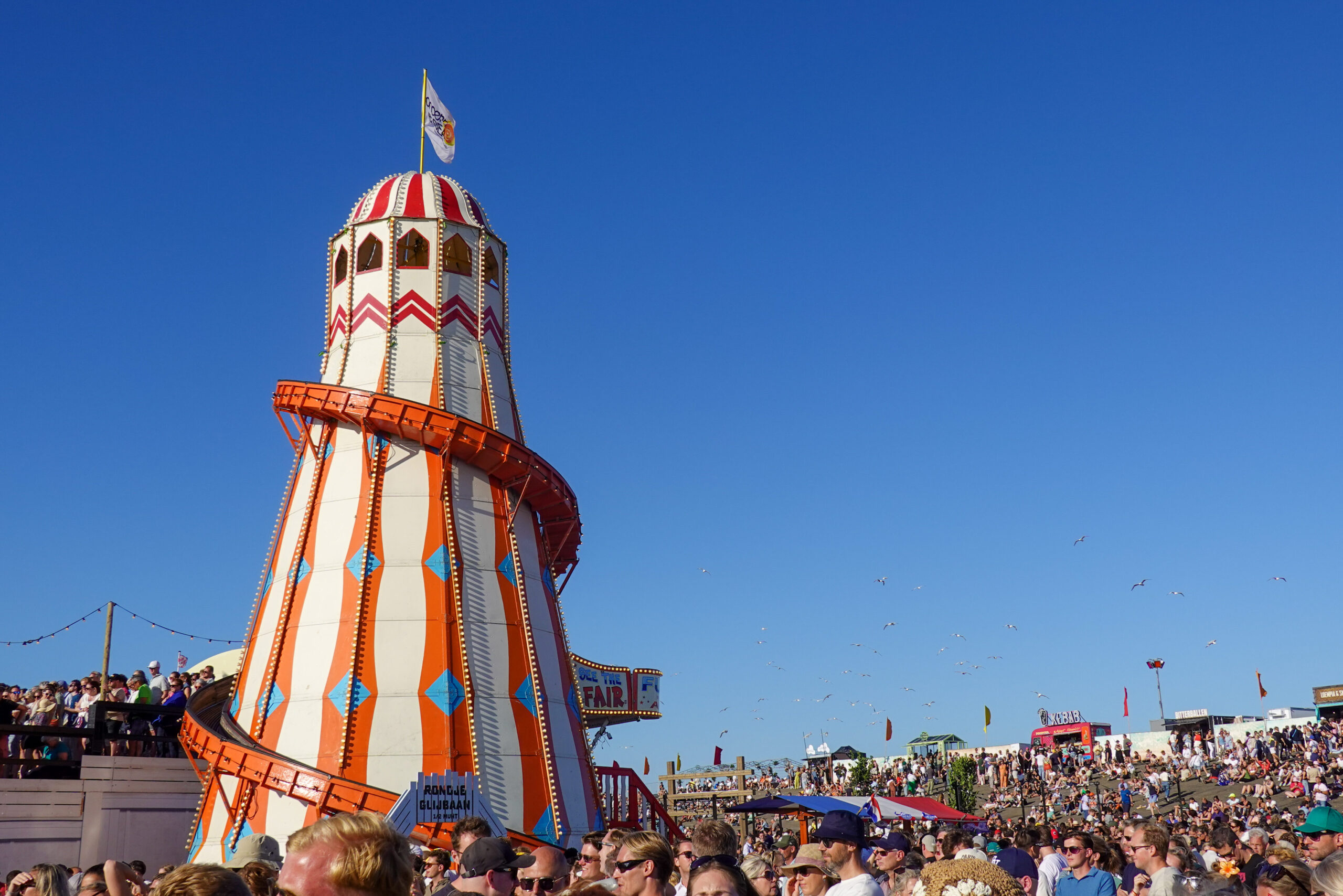 Een glijbaan die op Concert at Sea stond, de glijbaan is rood met witte strepen. Het is een gebouw waarin je naar boven kan klimmen en zodra je de glijbaan op gaat glij je rondom het gebouw weer naar beneden